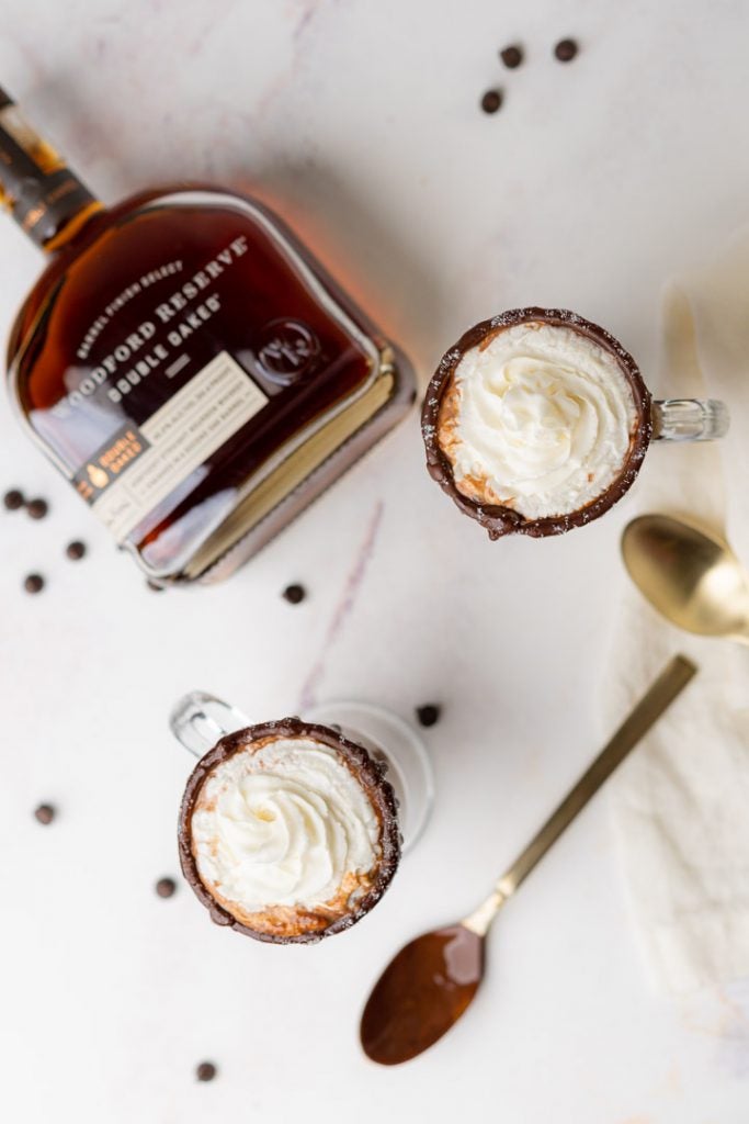Aerial view of Bourbon Hot Cocoa with a bottle of Woodford Reserve Double Oaked laying down in the background