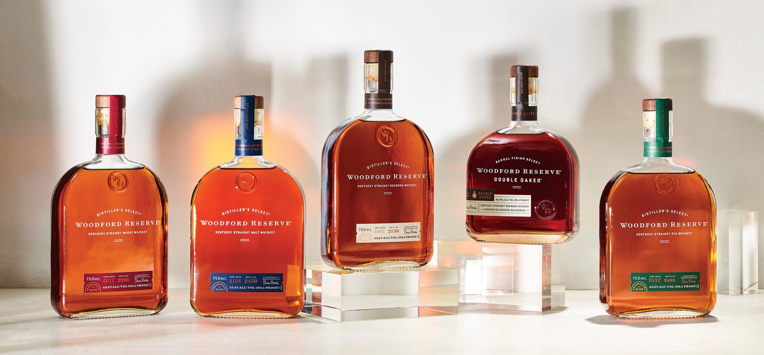 Display of Woodford Reserve bottles, including Woodford Reserve Kentucky Straight Wheat Whiskey, Kentucky Straight Malt Whiskey, Kentucky Straight Bourbon Whiskey, Double Oaked and Kentucky Straight Rye Whiskey.